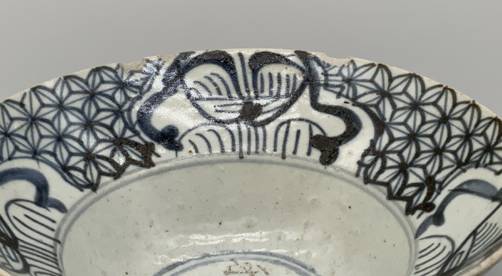 A 17th-century Chinese Swatow porcelain bowl featuring hand-painted underglaze blue geometric and floral motifs on an off-white glazed surface. View VIII