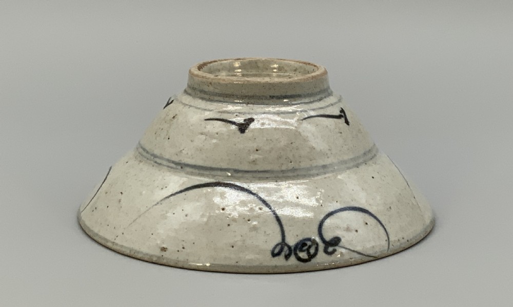 A 17th-century Chinese Swatow porcelain bowl featuring hand-painted underglaze blue geometric and floral motifs on an off-white glazed surface. View X