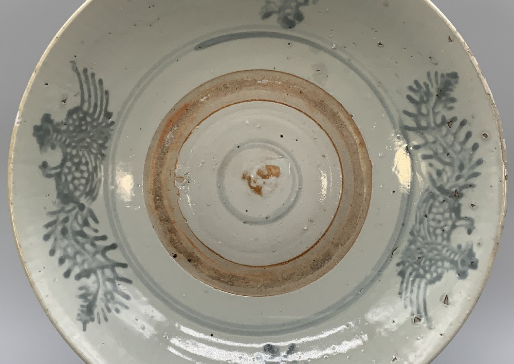 A large circular Ming Dynasty Swatow porcelain charger displaying hand-painted grey-blue phoenix motifs around an unglazed central ring. View IV
