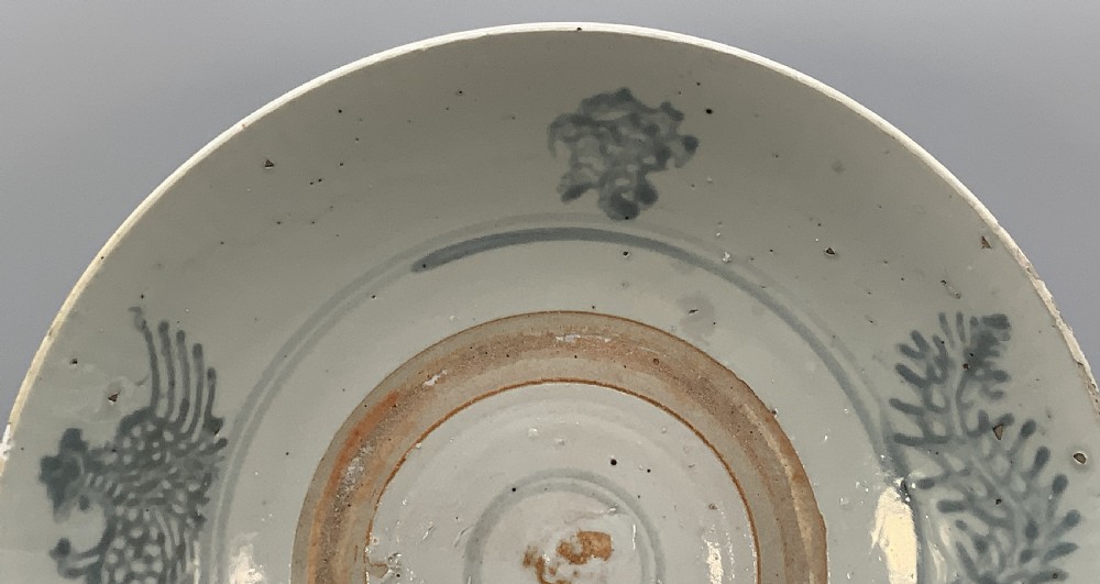 A large circular Ming Dynasty Swatow porcelain charger displaying hand-painted grey-blue phoenix motifs around an unglazed central ring. View V