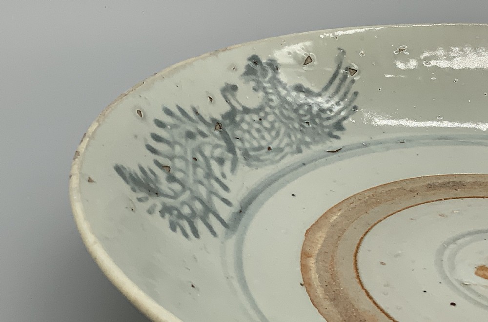 A large circular Ming Dynasty Swatow porcelain charger displaying hand-painted grey-blue phoenix motifs around an unglazed central ring. View XI
