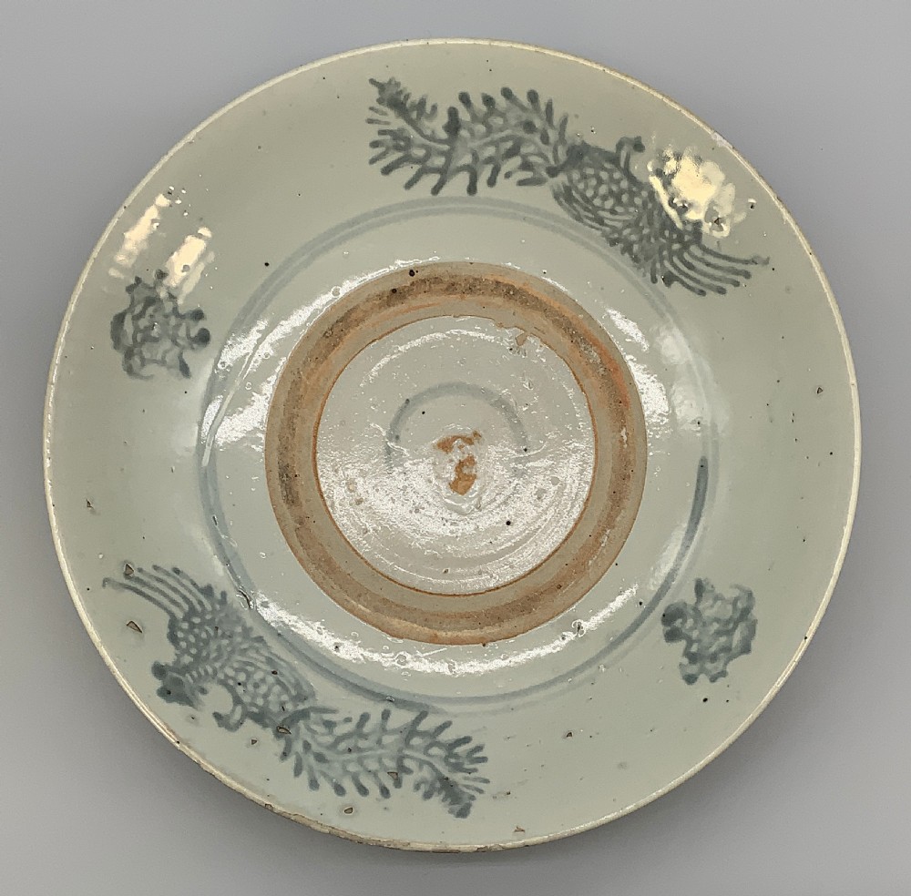 A large circular Ming Dynasty Swatow porcelain charger displaying hand-painted grey-blue phoenix motifs around an unglazed central ring. View XIV