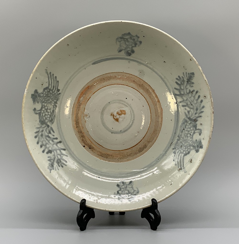 A large circular Ming Dynasty Swatow porcelain charger displaying hand-painted grey-blue phoenix motifs around an unglazed central ring. View XVI