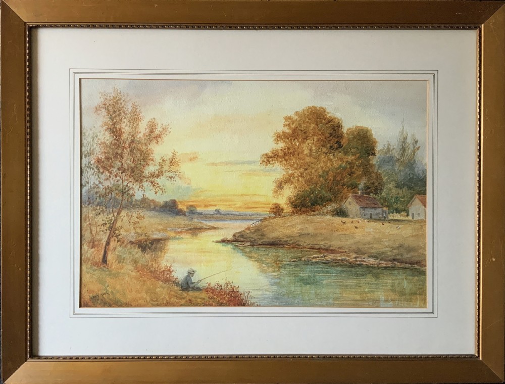 Framed antique watercolour painting depicting a figure fishing along a riverbank at sunset beside trees and cottages.