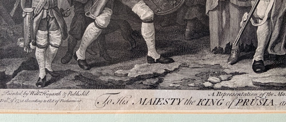 An 18th-century black and white satirical engraving depicting a crowded street scene with soldiers, housed in a black and gold frame with a cream mount. View XI