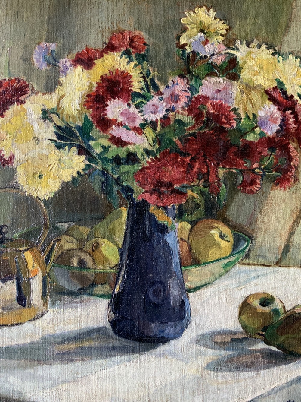 A framed 1931 impressionist oil painting depicting a vase of colourful flowers, a brass kettle, and fruit on a white draped table. View IV