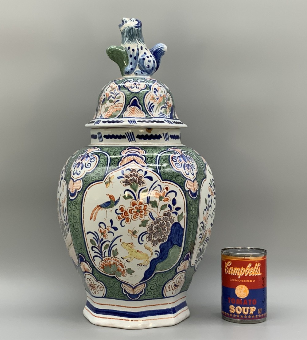 An octagonal tin-glazed ceramic baluster vase with a matching cover topped by a sculpted lion finial and decorated with multi-coloured floral panels. View III