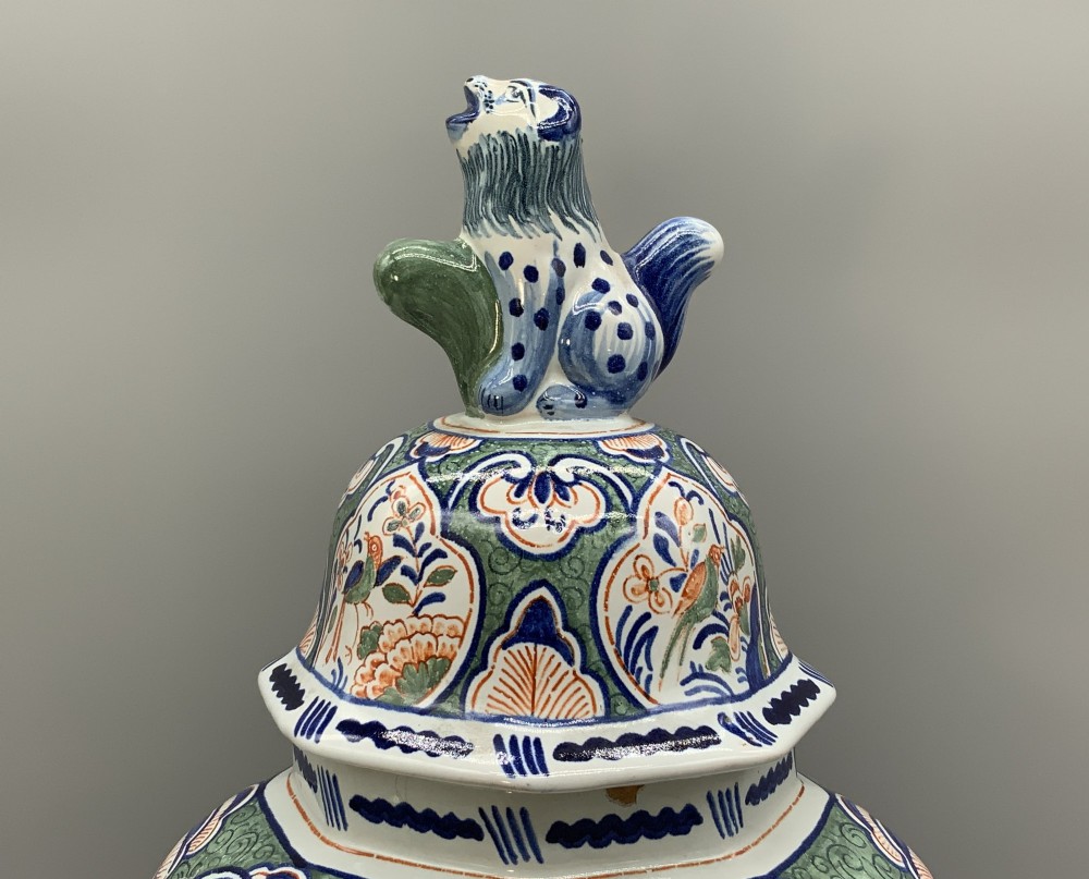 An octagonal tin-glazed ceramic baluster vase with a matching cover topped by a sculpted lion finial and decorated with multi-coloured floral panels. View V