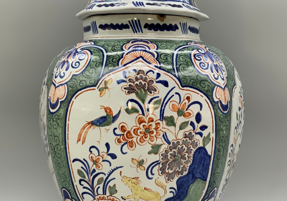 An octagonal tin-glazed ceramic baluster vase with a matching cover topped by a sculpted lion finial and decorated with multi-coloured floral panels. View VI