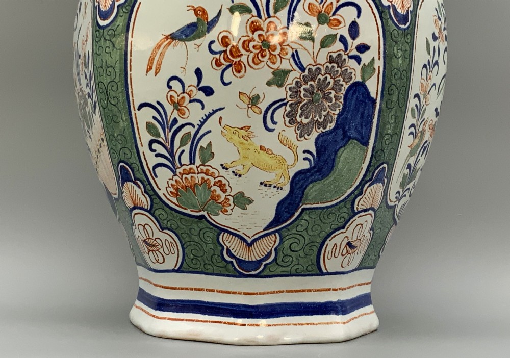 An octagonal tin-glazed ceramic baluster vase with a matching cover topped by a sculpted lion finial and decorated with multi-coloured floral panels. View VIII