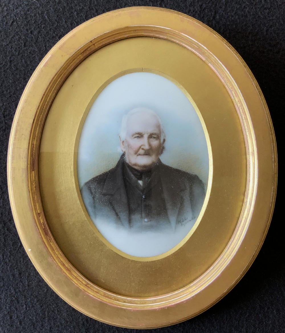 An oval Victorian miniature watercolour portrait of an elderly gentleman in a dark suit, set within a gilded frame.