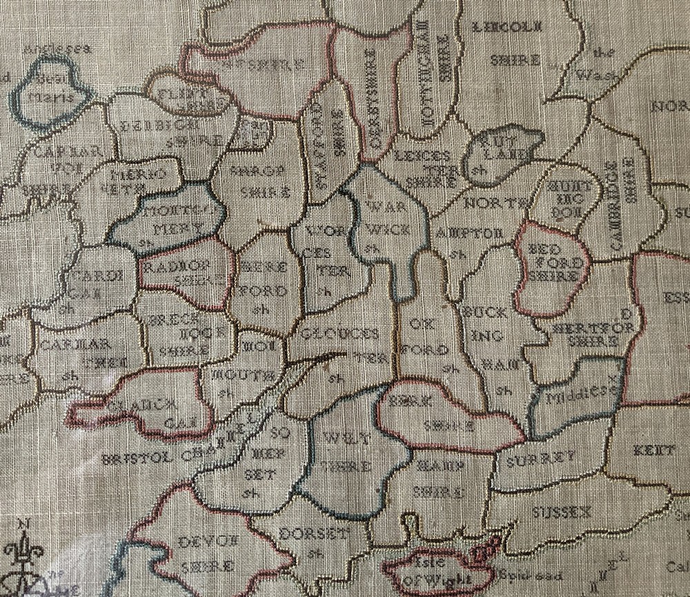 An oval Georgian embroidered needlepoint map of England and Wales with floral borders inside a gilt wooden frame. View IX