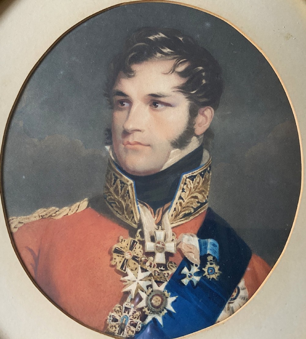 A circular gilt-framed miniature portrait print depicting a man in a red military uniform with medals and a blue sash. View III