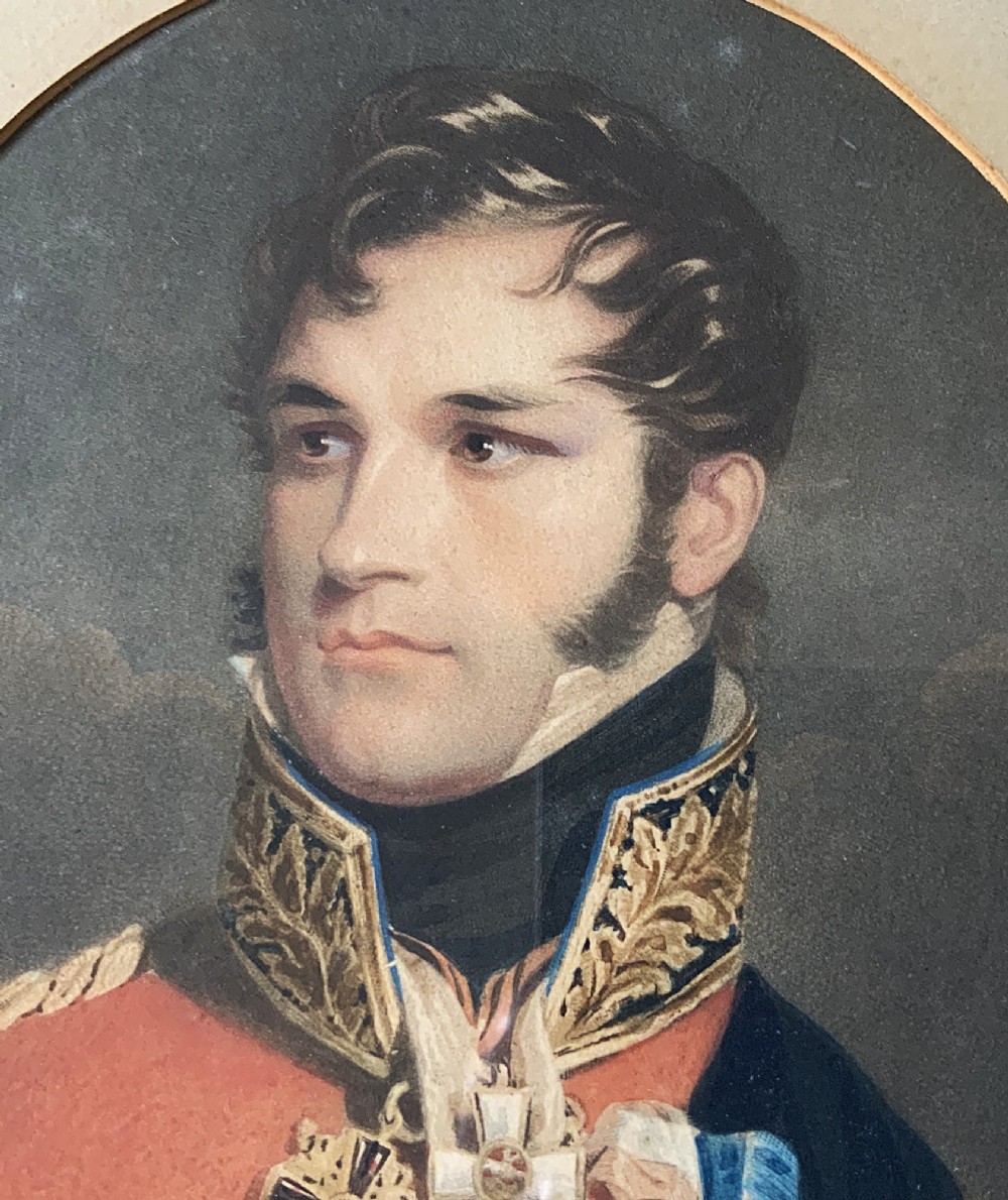 A circular gilt-framed miniature portrait print depicting a man in a red military uniform with medals and a blue sash. View V