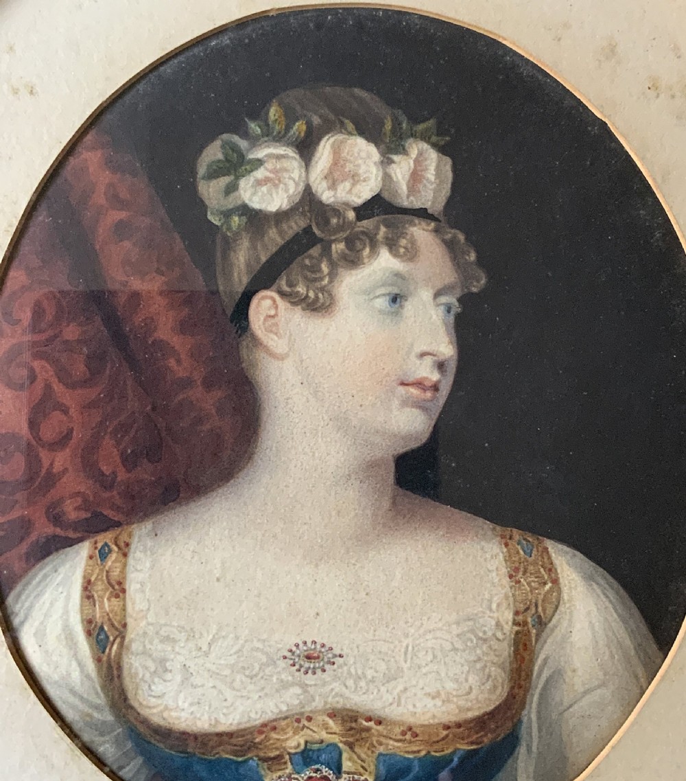 A circular gilt-framed hand-coloured miniature portrait depicting a young woman wearing a floral headband and blue dress. View IV