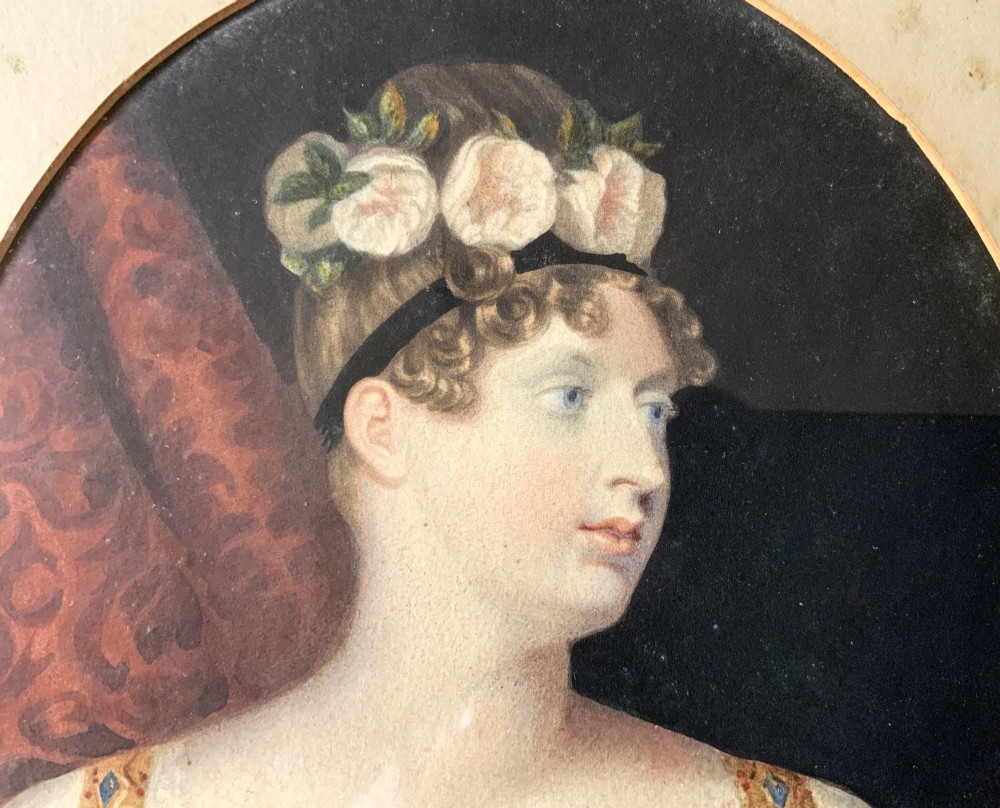 A circular gilt-framed hand-coloured miniature portrait depicting a young woman wearing a floral headband and blue dress. View VII