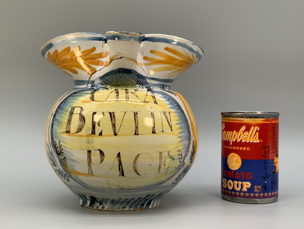 An antique Italian majolica earthenware pharmacy jug with hand-painted yellow, blue, and manganese script reading CARA BEVI IN PACE. View III