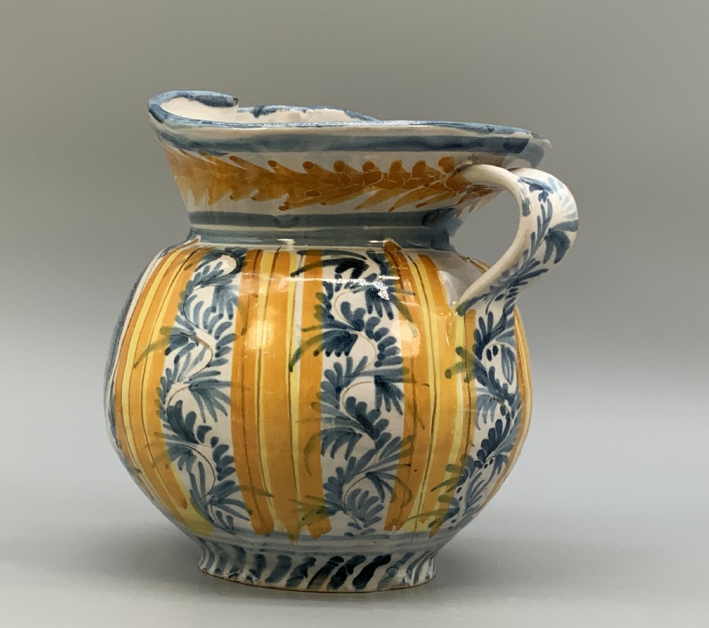 An antique Italian majolica earthenware pharmacy jug with hand-painted yellow, blue, and manganese script reading CARA BEVI IN PACE. View V