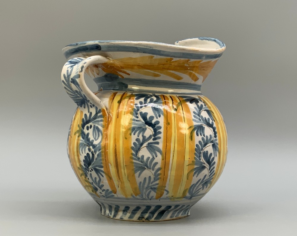 An antique Italian majolica earthenware pharmacy jug with hand-painted yellow, blue, and manganese script reading CARA BEVI IN PACE. View VII