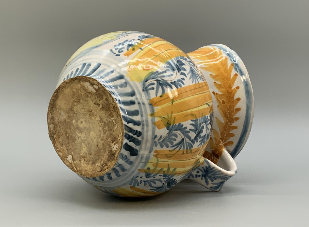 An antique Italian majolica earthenware pharmacy jug with hand-painted yellow, blue, and manganese script reading CARA BEVI IN PACE. View XIV