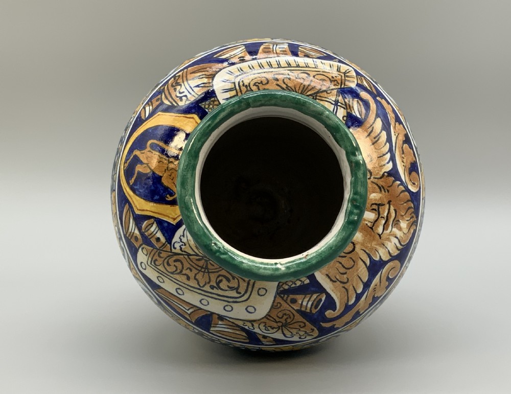 A tall hand-painted polychrome majolica ceramic vase featuring classical faces, winged cherub figures, and scrolling foliage on a circular pedestal foot. View XIV