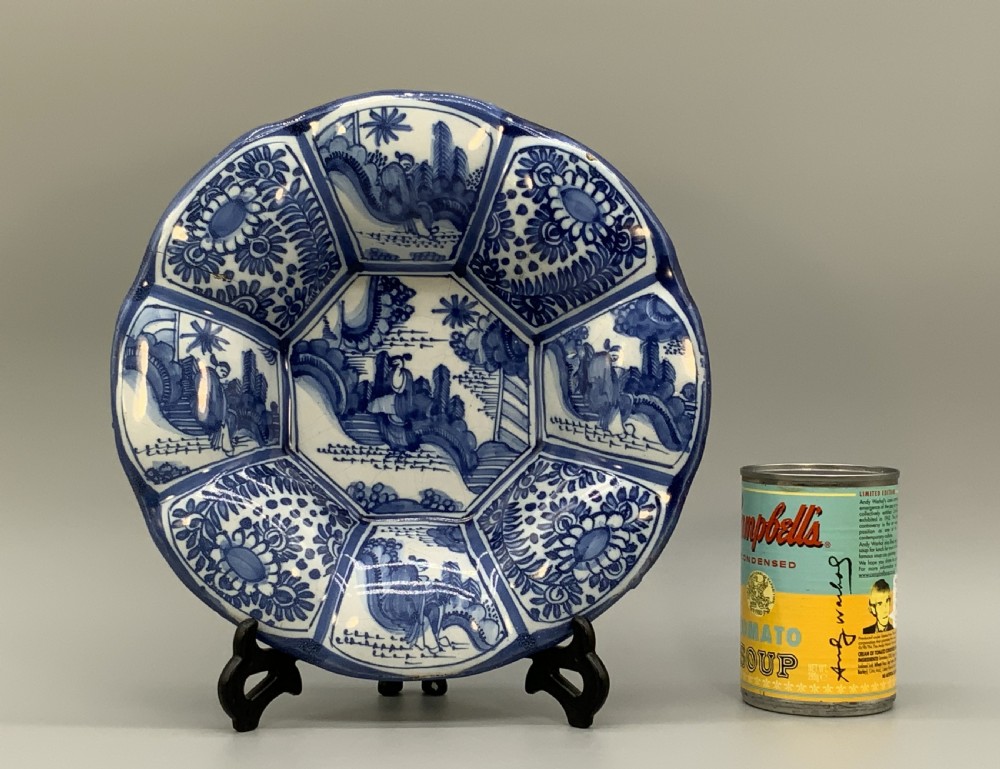 A blue and white tin-glazed earthenware lobed dish featuring panelled borders and a central Chinoiserie landscape scene. View III