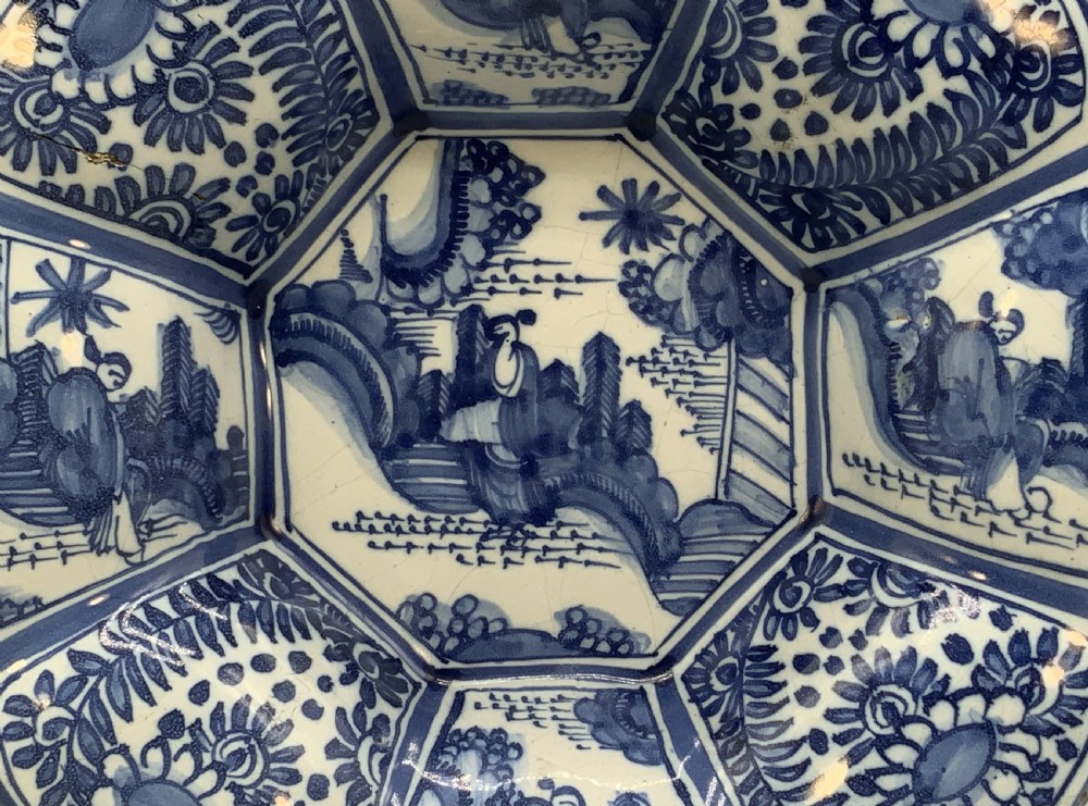 A blue and white tin-glazed earthenware lobed dish featuring panelled borders and a central Chinoiserie landscape scene. View IV