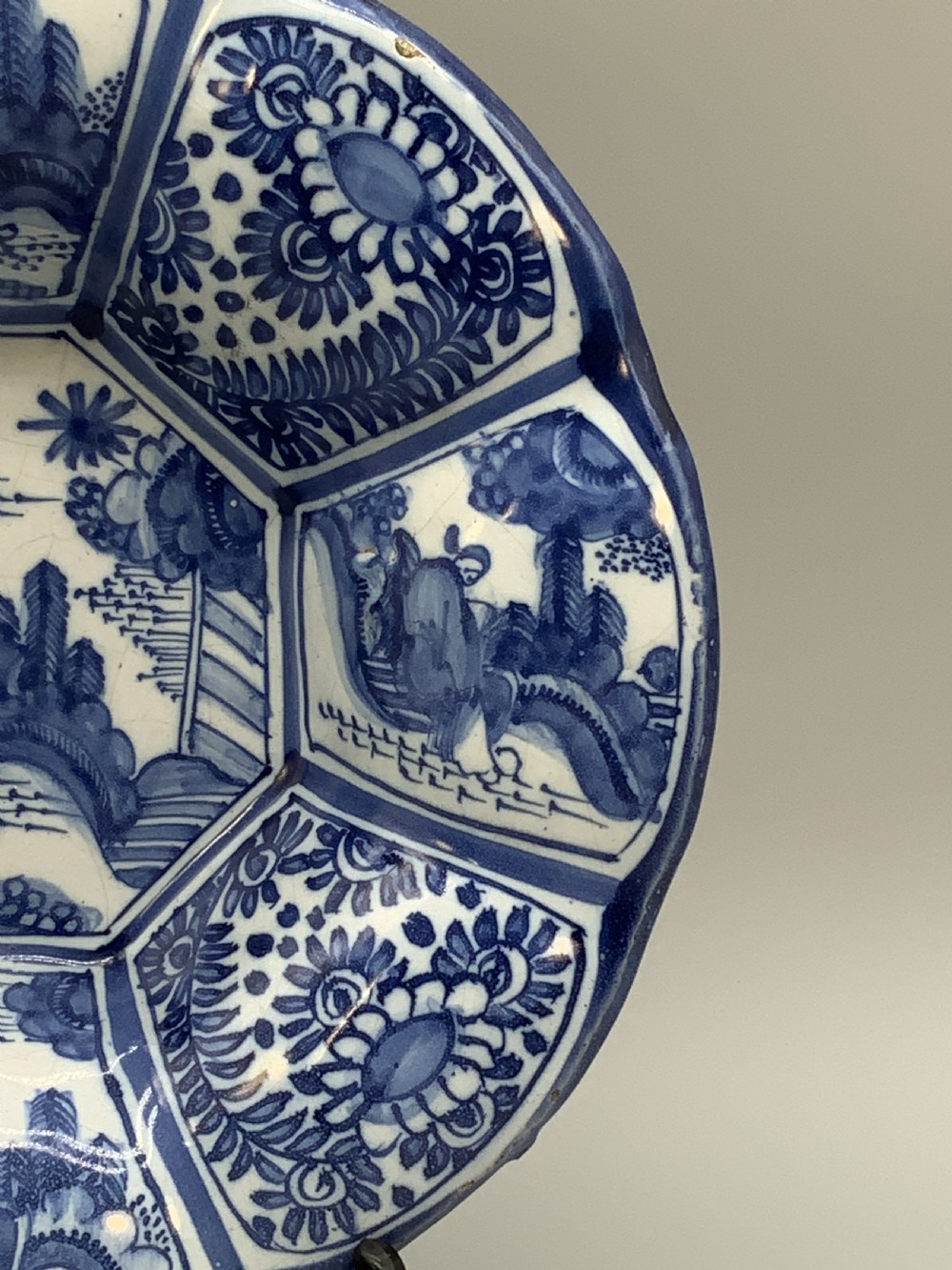 A blue and white tin-glazed earthenware lobed dish featuring panelled borders and a central Chinoiserie landscape scene. View VI