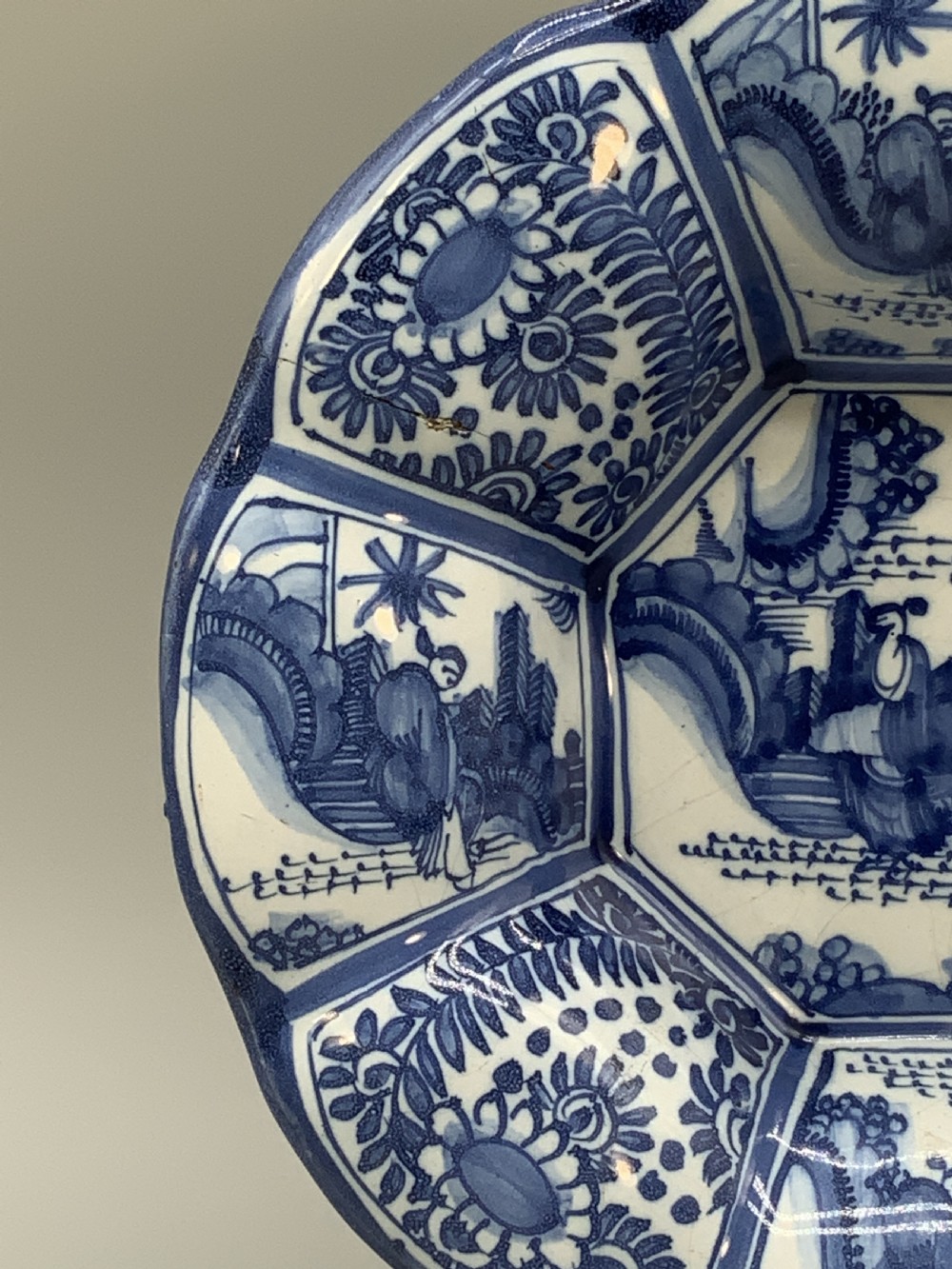 A blue and white tin-glazed earthenware lobed dish featuring panelled borders and a central Chinoiserie landscape scene. View VIII