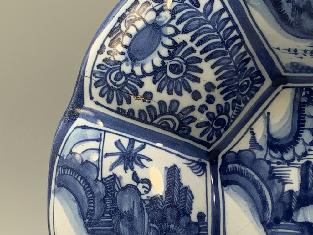 A blue and white tin-glazed earthenware lobed dish featuring panelled borders and a central Chinoiserie landscape scene. View XV