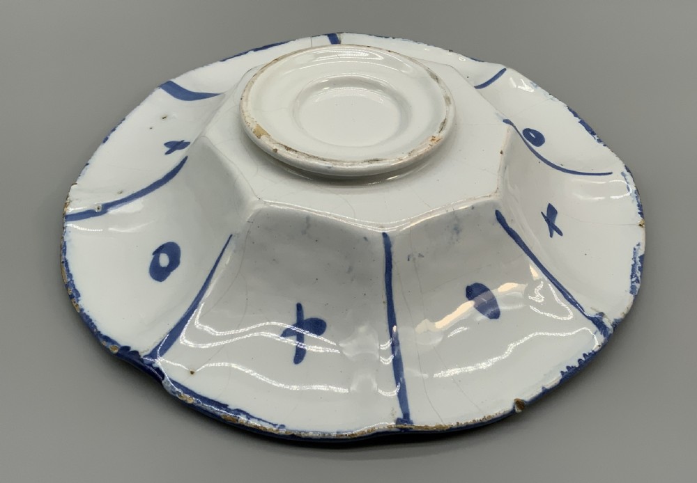 A blue and white tin-glazed earthenware lobed dish featuring panelled borders and a central Chinoiserie landscape scene. View XVII