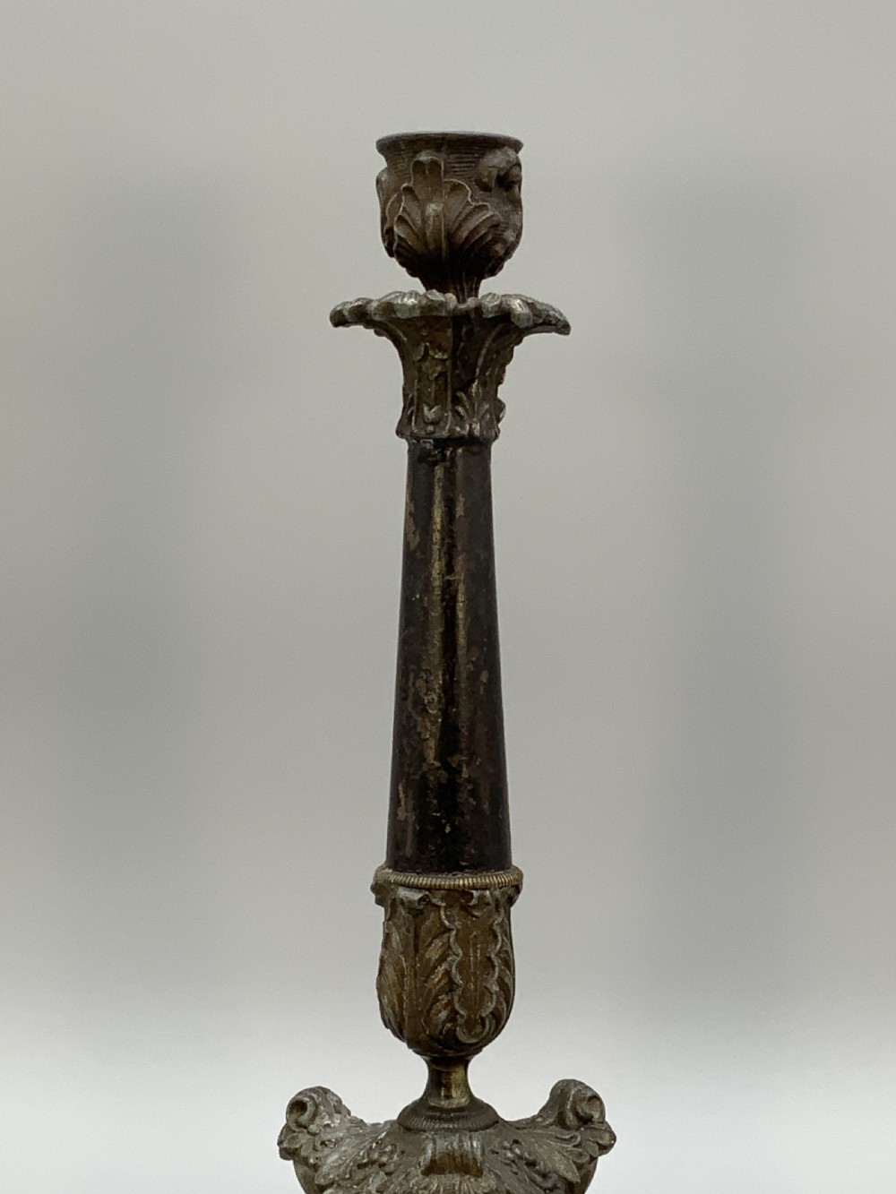 A pair of nineteenth-century French Empire metal candlesticks featuring dark tapered columns, ornate acanthus leaf capitals, and decorative triangular bases. View VI