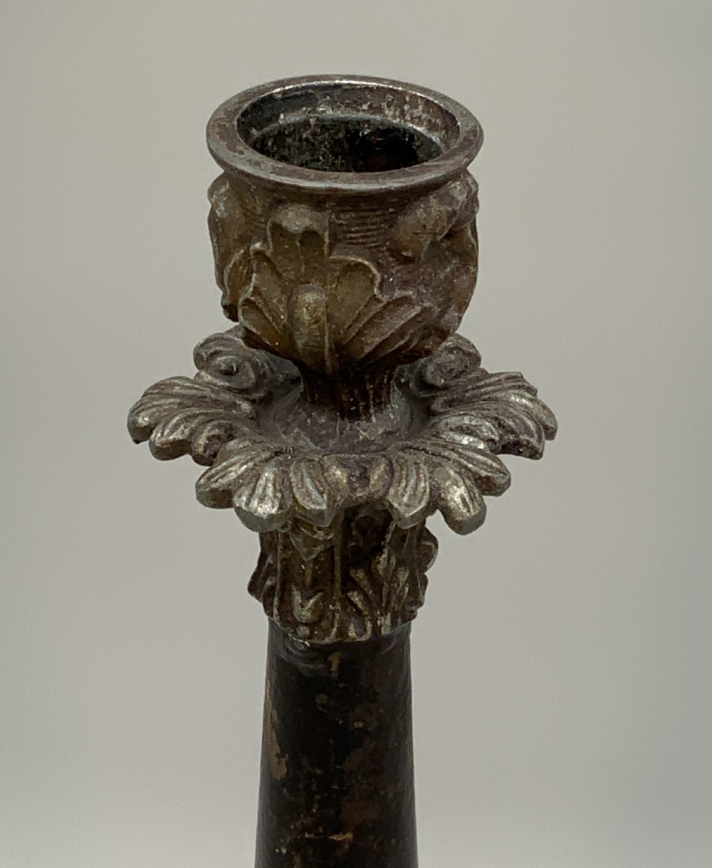 A pair of nineteenth-century French Empire metal candlesticks featuring dark tapered columns, ornate acanthus leaf capitals, and decorative triangular bases. View VII