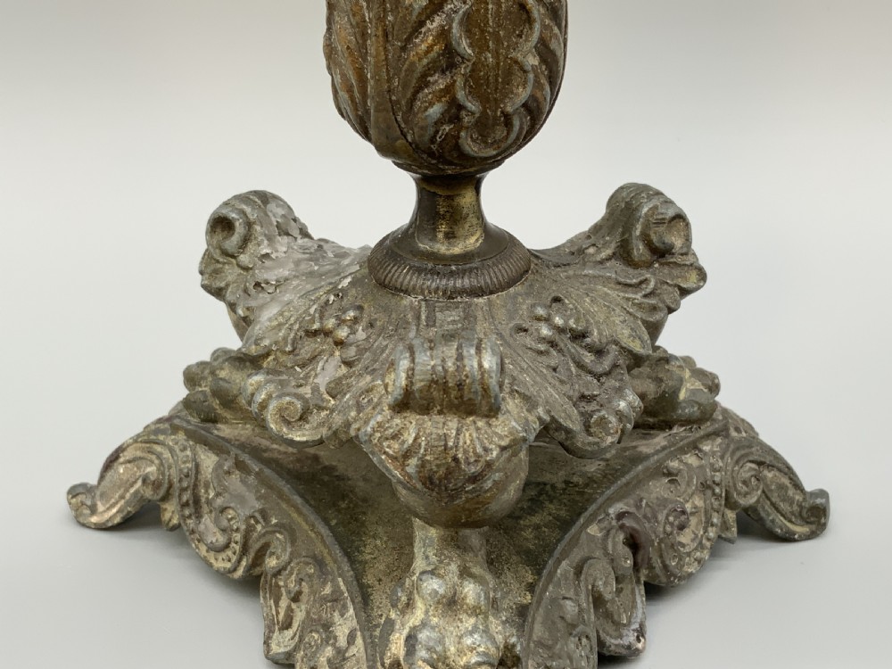 A pair of nineteenth-century French Empire metal candlesticks featuring dark tapered columns, ornate acanthus leaf capitals, and decorative triangular bases. View IX