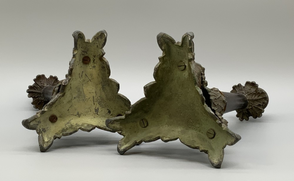A pair of nineteenth-century French Empire metal candlesticks featuring dark tapered columns, ornate acanthus leaf capitals, and decorative triangular bases. View XII