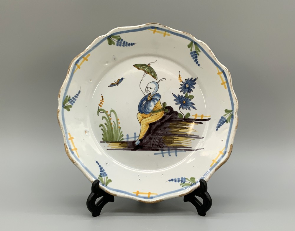 An 18th-century French tin-glazed earthenware charger with a lobed border featuring hand-painted Chinoiserie figures and floral motifs.