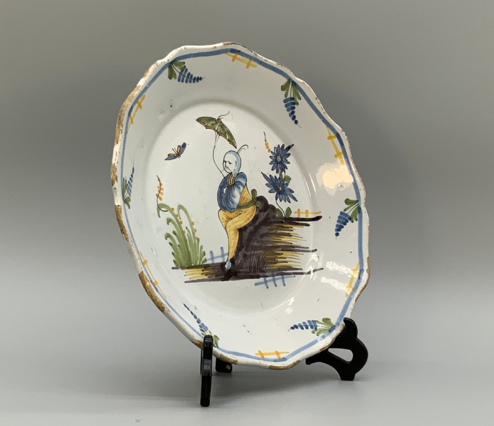 An 18th-century French tin-glazed earthenware charger with a lobed border featuring hand-painted Chinoiserie figures and floral motifs. View X
