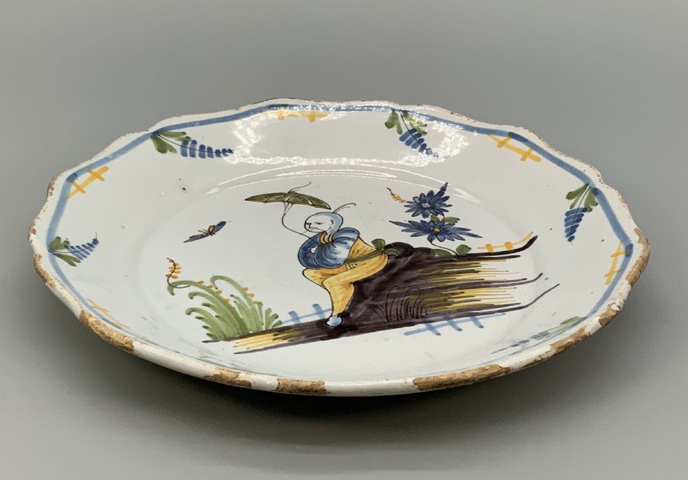 An 18th-century French tin-glazed earthenware charger with a lobed border featuring hand-painted Chinoiserie figures and floral motifs. View XIV