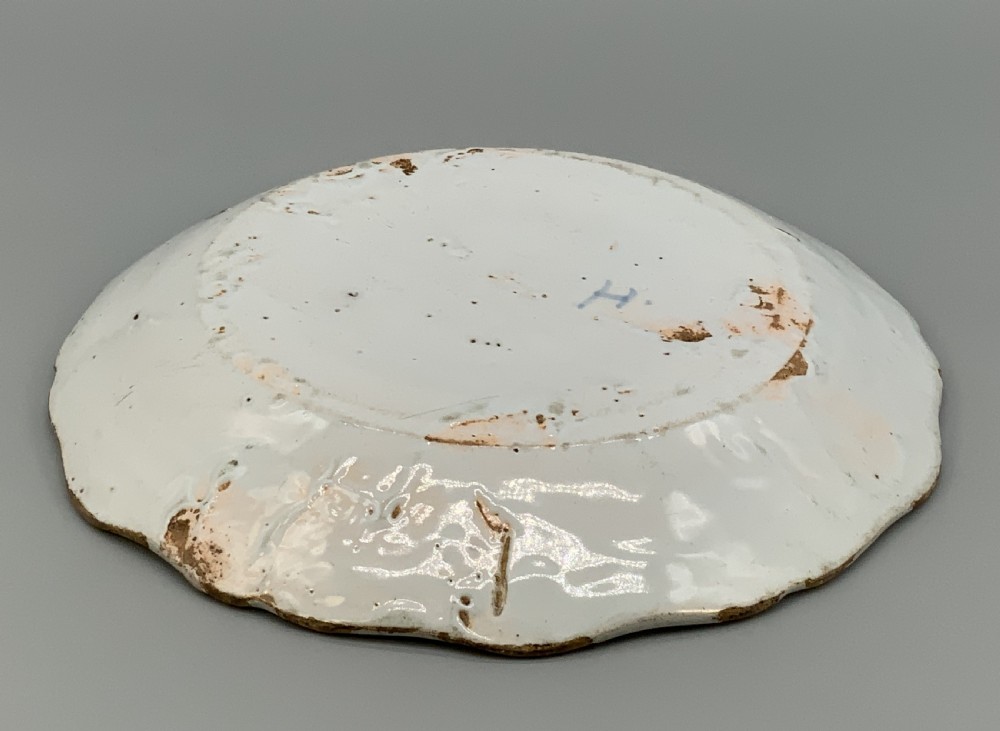 An 18th-century French tin-glazed earthenware charger with a lobed border featuring hand-painted Chinoiserie figures and floral motifs. View XV