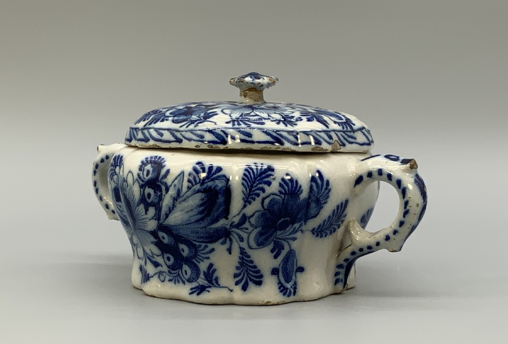 A 17th-century English Delftware lidded pot painted with cobalt blue floral motifs, featuring two side loop handles and a knopped lid. View IV