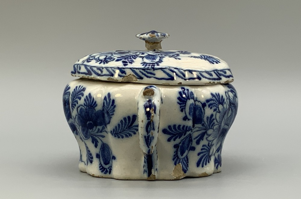 A 17th-century English Delftware lidded pot painted with cobalt blue floral motifs, featuring two side loop handles and a knopped lid. View V