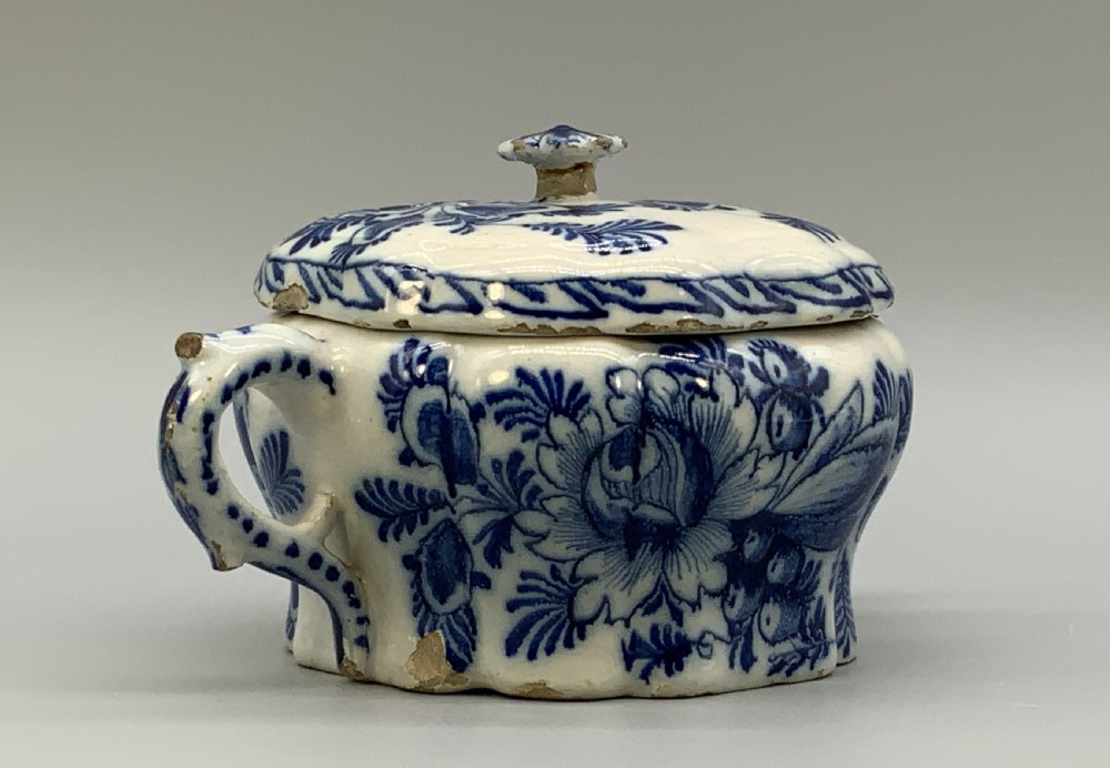A 17th-century English Delftware lidded pot painted with cobalt blue floral motifs, featuring two side loop handles and a knopped lid. View VI
