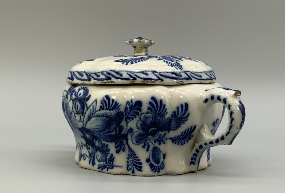 A 17th-century English Delftware lidded pot painted with cobalt blue floral motifs, featuring two side loop handles and a knopped lid. View VII