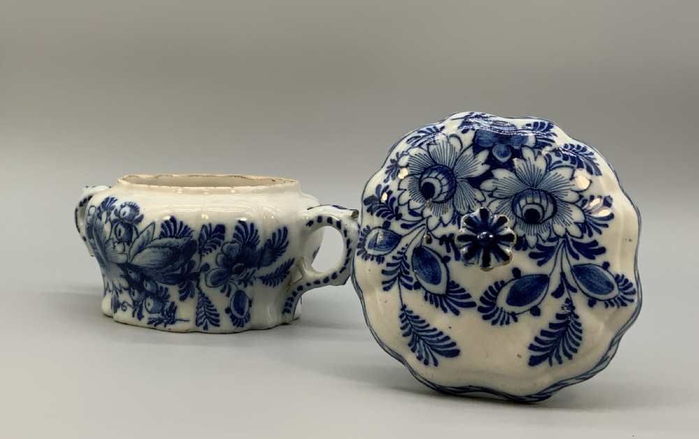 A 17th-century English Delftware lidded pot painted with cobalt blue floral motifs, featuring two side loop handles and a knopped lid. View VIII
