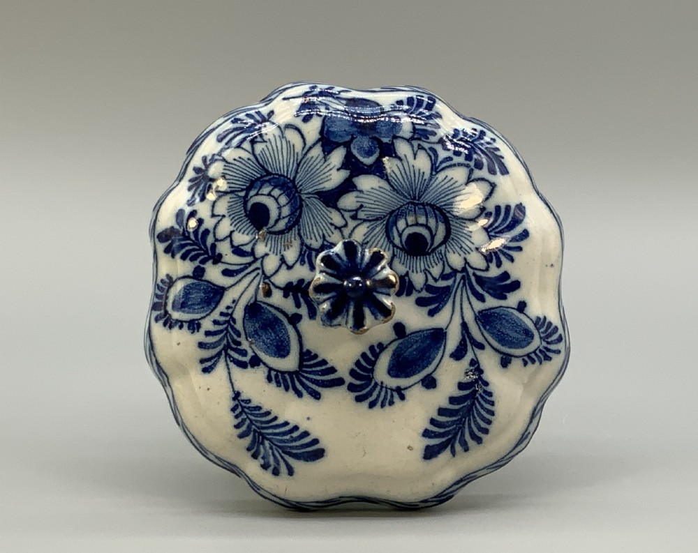 A 17th-century English Delftware lidded pot painted with cobalt blue floral motifs, featuring two side loop handles and a knopped lid. View IX