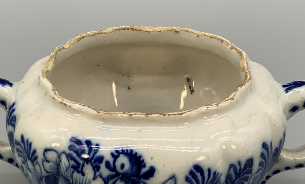 A 17th-century English Delftware lidded pot painted with cobalt blue floral motifs, featuring two side loop handles and a knopped lid. View XI
