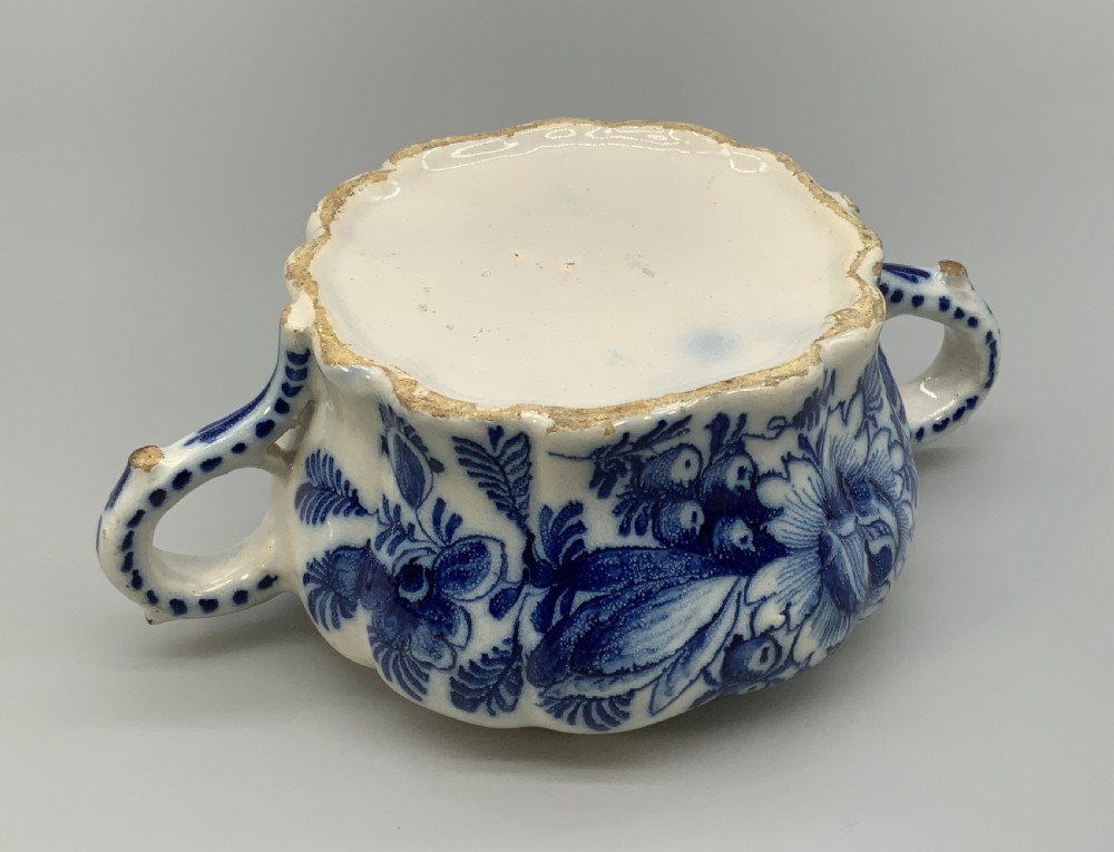 A 17th-century English Delftware lidded pot painted with cobalt blue floral motifs, featuring two side loop handles and a knopped lid. View XVI