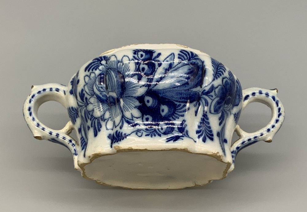 A 17th-century English Delftware lidded pot painted with cobalt blue floral motifs, featuring two side loop handles and a knopped lid. View XVIII