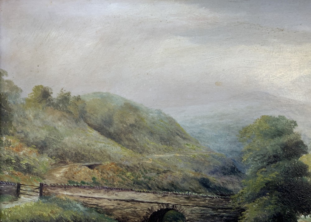 A 19th-century Victorian oil painting depicting a British rural landscape with a stone arch bridge, framed in an ornate gilded wooden frame. View X