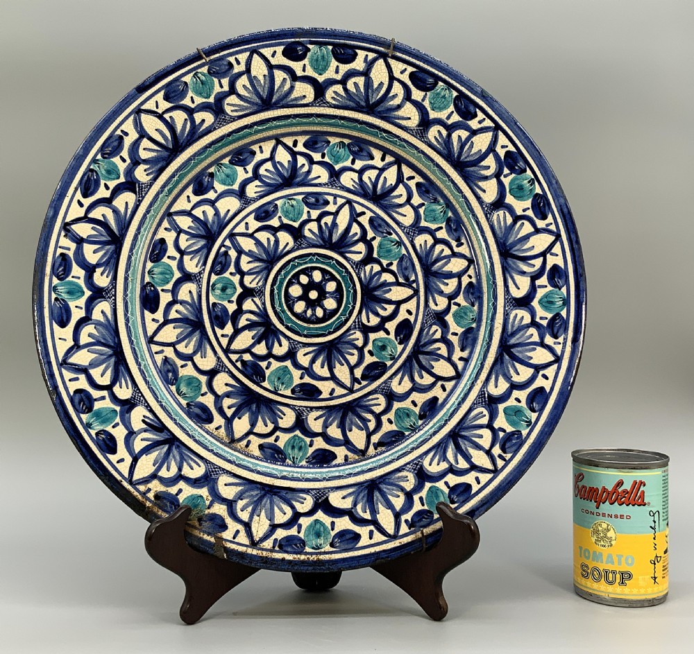 A large round tin-glazed earthenware charger plate featuring concentric hand-painted Moorish floral motifs in cobalt blue and turquoise on a cream ground. View III